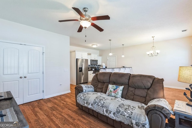living room with visible vents, dark wood finished floors, baseboards, and ceiling fan with notable chandelier