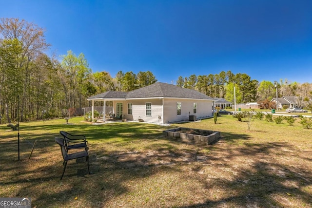 back of house with a yard and a garden