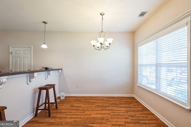 dining space featuring visible vents, baseboards, a notable chandelier, and wood finished floors