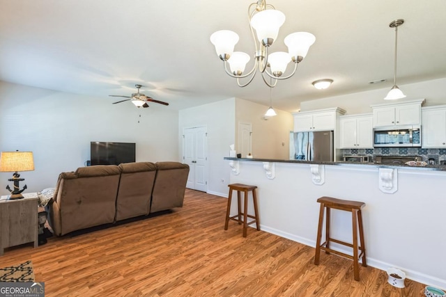kitchen featuring a kitchen breakfast bar, open floor plan, white cabinetry, dark countertops, and stainless steel appliances