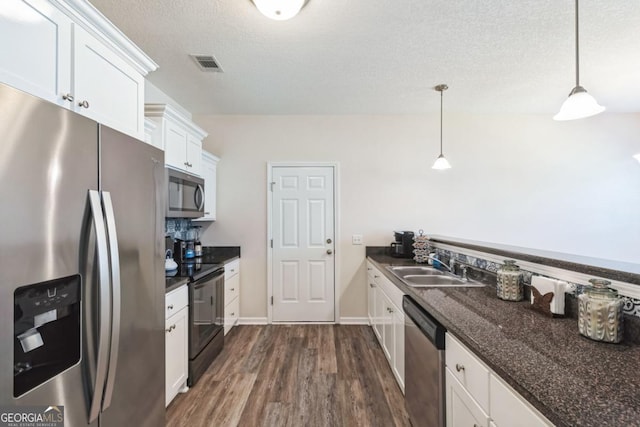 kitchen with visible vents, white cabinets, a sink, appliances with stainless steel finishes, and dark wood finished floors