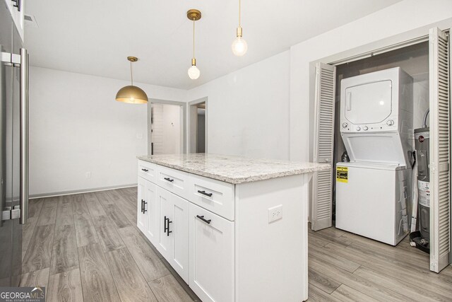 609 Spring St, Atlanta, GA 30354 - kitchen featuring stacked washer / drying machine, light wood-style flooring, white cabinetry, a center island, and light stone counters