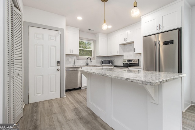 609 Spring St, Atlanta, GA 30354 - kitchen featuring stainless steel appliances, white cabinets, decorative backsplash, light wood-type flooring, and a kitchen island