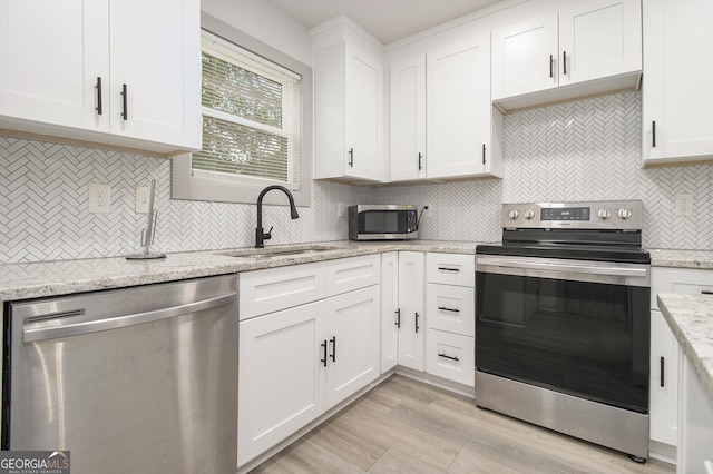 609 Spring St, Atlanta, GA 30354 - kitchen with appliances with stainless steel finishes, a sink, white cabinetry, backsplash, and light wood-type flooring
