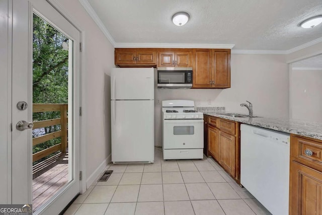 kitchen with brown cabinetry, white appliances, a sink, and crown molding