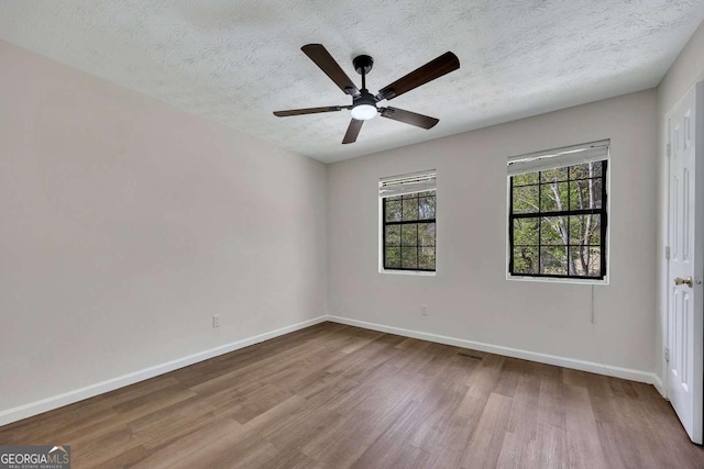 empty room featuring baseboards, a ceiling fan, wood finished floors, and a textured ceiling