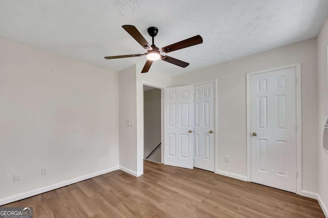 unfurnished bedroom with ceiling fan, a textured ceiling, light wood finished floors, and baseboards
