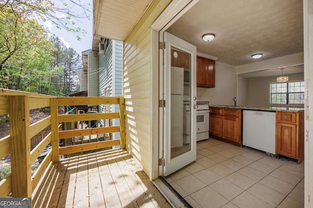 exterior space with a sink, ornamental molding, white appliances, a peninsula, and brown cabinetry