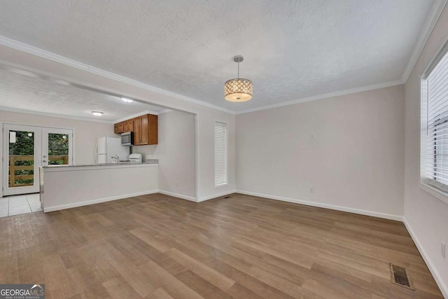 unfurnished living room with a wealth of natural light, light wood-style floors, and a textured ceiling