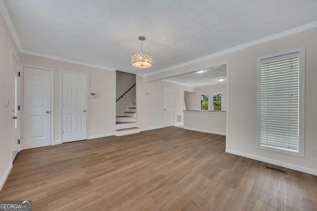 unfurnished living room featuring a textured ceiling, wood finished floors, and stairs