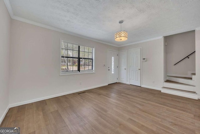 interior space featuring crown molding, wood finished floors, baseboards, and stairs