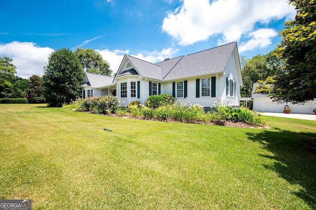 view of front of property featuring a front lawn, a shingled roof, and a garage