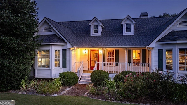 view of front of house with roof with shingles, a chimney, and covered porch
