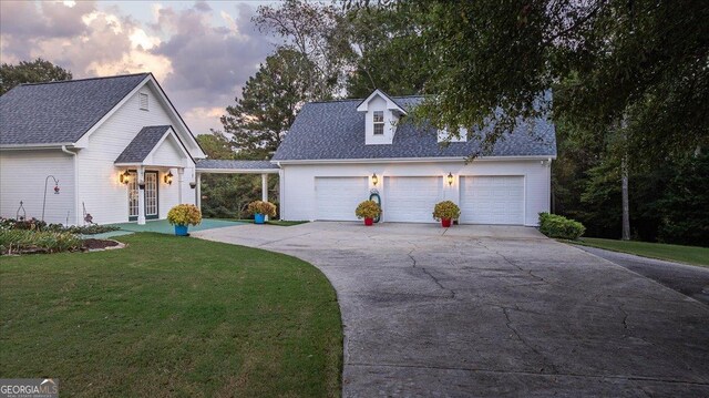 view of front facade with a front lawn, a shingled roof, and concrete driveway