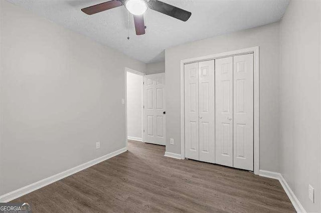 unfurnished bedroom with a ceiling fan, wood finished floors, baseboards, and a closet