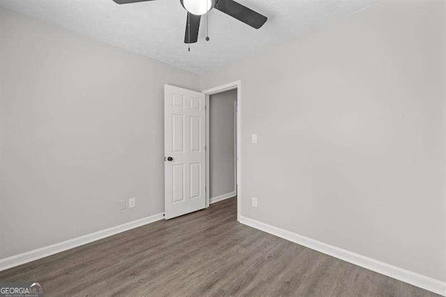 spare room with baseboards, ceiling fan, wood finished floors, and a textured ceiling