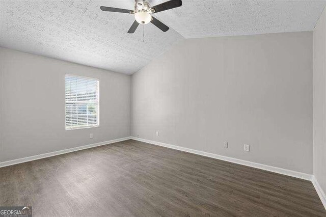 empty room with dark wood-style flooring, ceiling fan, lofted ceiling, and baseboards