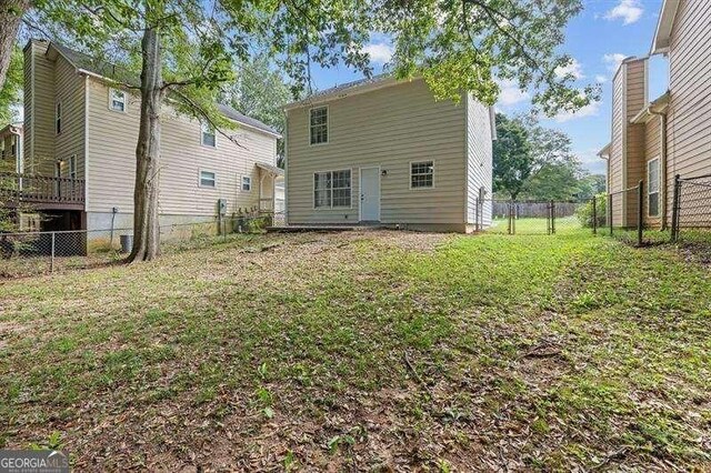 back of house with a yard and a fenced backyard
