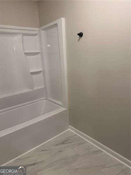 full bathroom featuring marble finish floor, baseboards, and shower / washtub combination