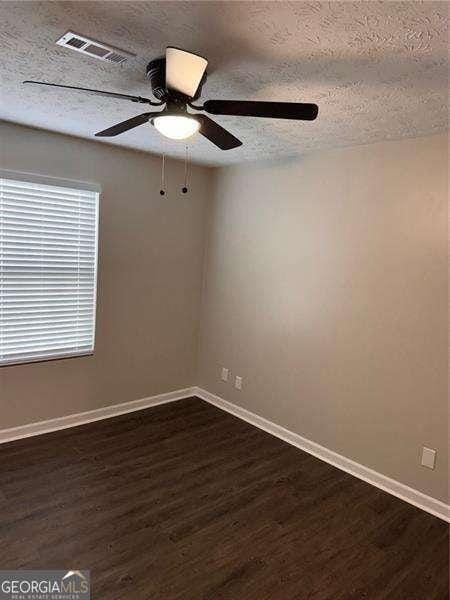 unfurnished room with visible vents, baseboards, dark wood-style flooring, a ceiling fan, and a textured ceiling