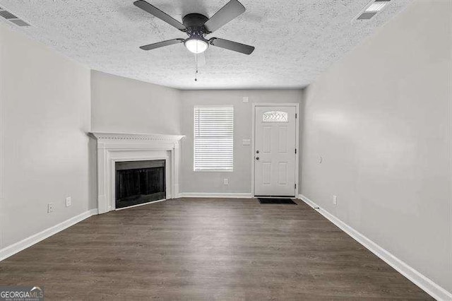 unfurnished living room with baseboards, a fireplace, visible vents, ceiling fan, and wood finished floors