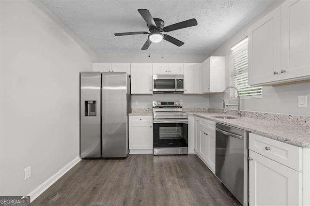 kitchen with dark wood-type flooring, a textured ceiling, white cabinetry, a sink, and stainless steel appliances