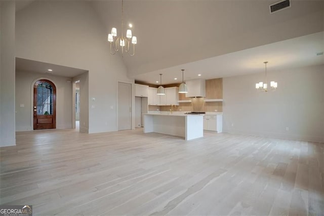 310 Arbor Garden Cir, Newnan, GA 30265 - unfurnished living room with a chandelier, light wood finished floors, recessed lighting, high vaulted ceiling, and a sink