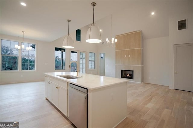 310 Arbor Garden Cir, Newnan, GA 30265 - kitchen with stainless steel dishwasher, a sink, a chandelier, light wood-style flooring, and high vaulted ceiling