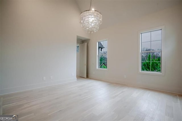 310 Arbor Garden Cir, Newnan, GA 30265 - spare room with a chandelier, light wood-style flooring, baseboards, and a towering ceiling