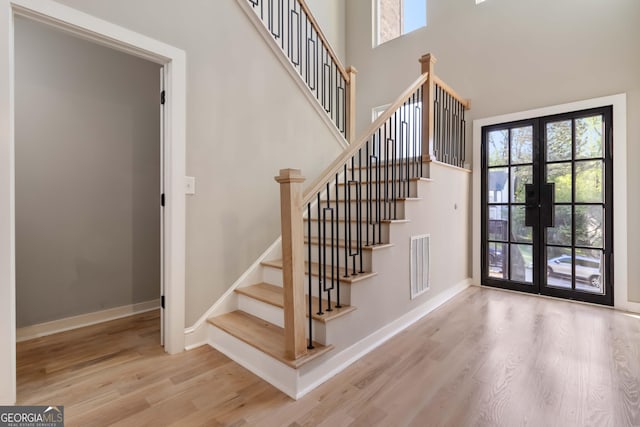 6960 Dockbridge Way, Stone Mountain, GA 30087 - staircase with french doors, wood finished floors, healthy amount of natural light, and a towering ceiling