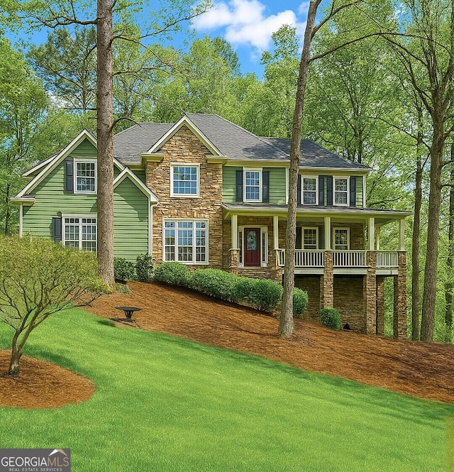 view of front of property with a front lawn, a shingled roof, stone siding, and covered porch