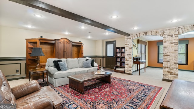 living area with recessed lighting, arched walkways, wainscoting, and beam ceiling