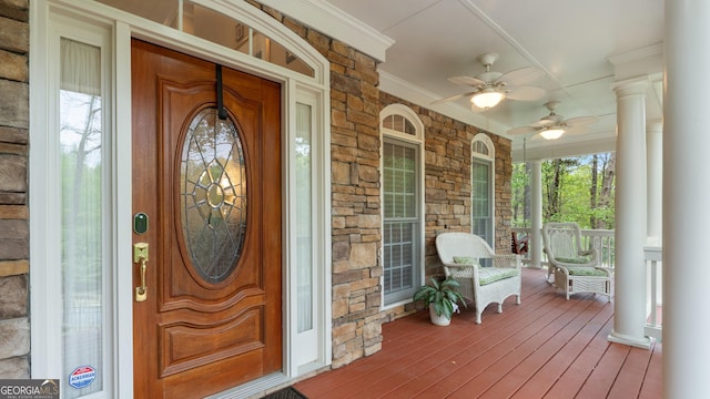view of exterior entry with ceiling fan, stone siding, and covered porch