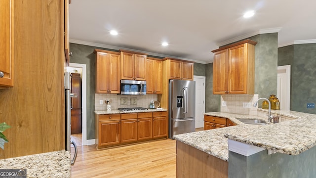 kitchen with a sink, ornamental molding, a peninsula, and stainless steel appliances