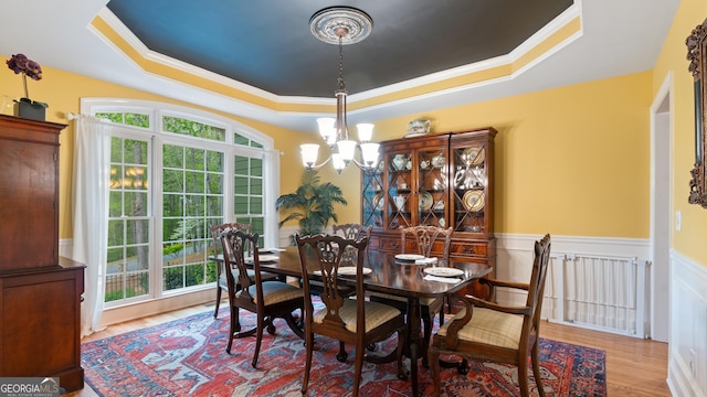 dining area featuring a tray ceiling, crown molding, wood finished floors, and an inviting chandelier