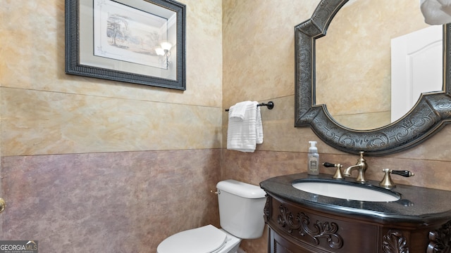 half bath with vanity, tile walls, and toilet