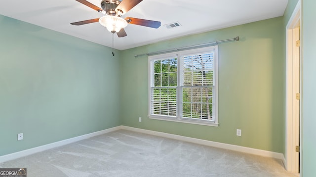 carpeted spare room with baseboards, a ceiling fan, and visible vents