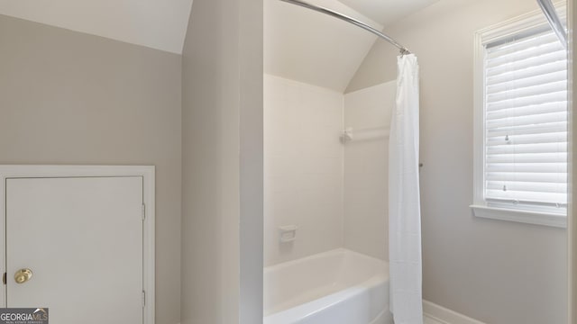 full bath featuring shower / tub combo, baseboards, and vaulted ceiling