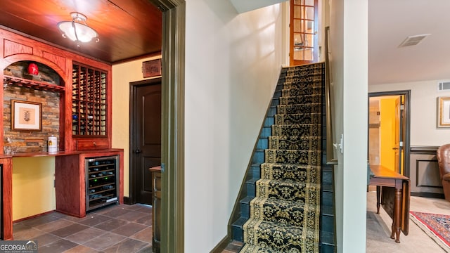wine area featuring wine cooler, visible vents, and indoor bar
