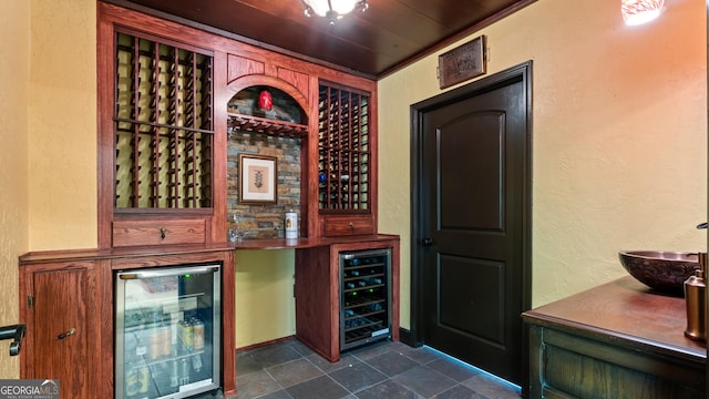 wine cellar with wine cooler, a textured wall, and stone finish flooring