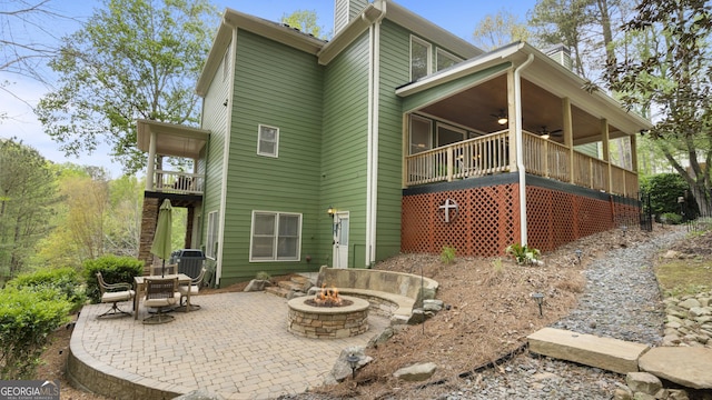 rear view of property featuring a patio, a chimney, an outdoor fire pit, and ceiling fan