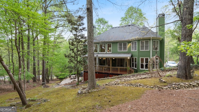 back of house featuring a chimney and covered porch