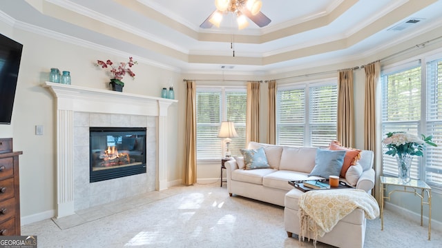 living room featuring a tray ceiling, crown molding, ceiling fan, and visible vents