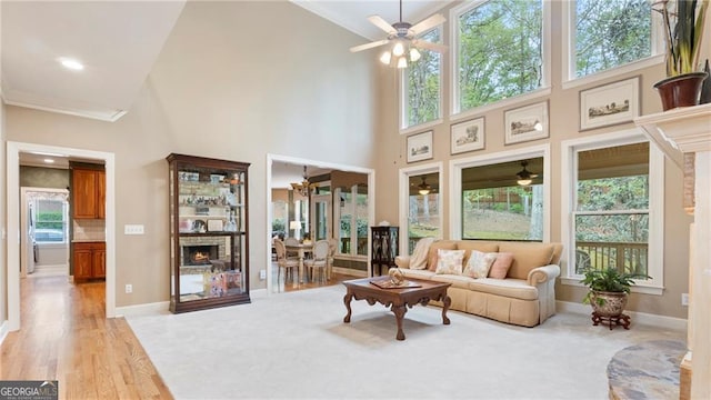 104 Kremer Falls Trce, Canton, GA 30114 - living room featuring ceiling fan, ornamental molding, a high ceiling, a lit fireplace, and baseboards