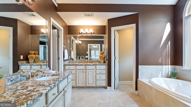 bathroom with a sink, visible vents, two vanities, and a garden tub