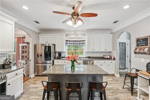 698 Jefferson Hwy, Winder, GA 30680 - kitchen featuring appliances with stainless steel finishes, a breakfast bar area, a ceiling fan, white cabinets, and decorative backsplash