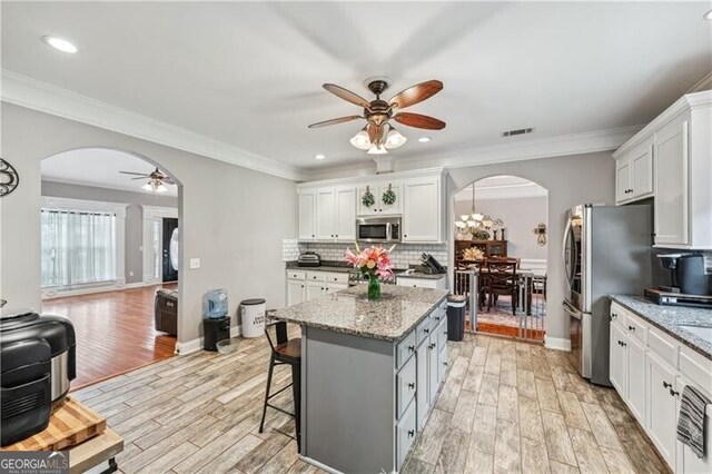 698 Jefferson Hwy, Winder, GA 30680 - kitchen featuring arched walkways, stainless steel appliances, ceiling fan, backsplash, and white cabinets