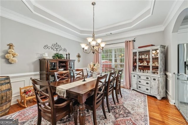 698 Jefferson Hwy, Winder, GA 30680 - dining space with a tray ceiling, a chandelier, arched walkways, ornamental molding, and light wood-style flooring