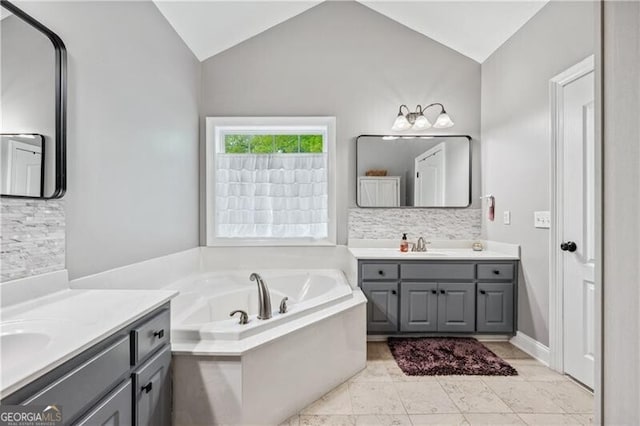 698 Jefferson Hwy, Winder, GA 30680 - bathroom featuring two vanities, lofted ceiling, tasteful backsplash, and a garden tub