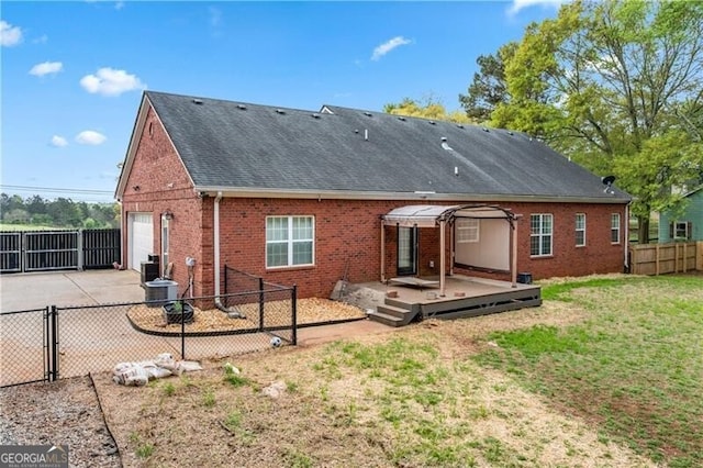 698 Jefferson Hwy, Winder, GA 30680 - rear view of house with brick siding, a fenced backyard, a wooden deck, driveway, and roof with shingles
